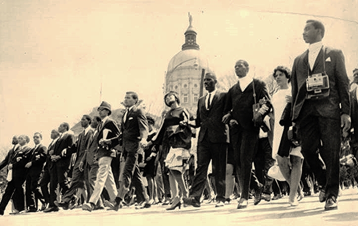 Sepia-tone photo showing a line of Black funeral marchers walking downhill past the Georgia Capitol building. The Capitol’s dome appears in the background.