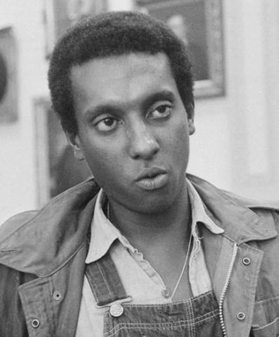 Black and white photo of Stokely Carmichael, the future Kwame Ture, when he was chairman of the Student Non-Violent Coordinating Committee (SNCC, pronounced “SNICK”). This photo from 1966 shows Carmichael in Mississippi wearing blue denim overalls in solidarity with poor Black tenant farmers and Black working people generally.