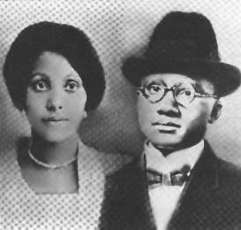 Black and white composite photo, showing Louise Little at left, Malcom Little at right. Louise has dark hair, perhaps in a bun, and wears a light-colored checkered dress with a necklace. Earl is shown dressed in a dark suit, white high-collar shirt, and bowtie; he wears glasses and a dark fedora.