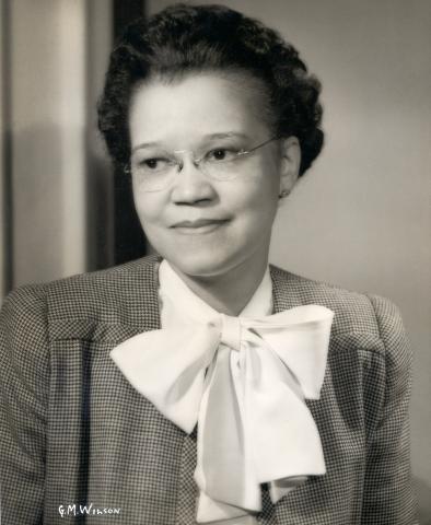 Black and white portrait photograph of Sadie T.M. Alexander wearing glasses, print jacket, and blouse with large bow.